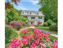 Charming two-story home with lush landscaping, including vibrant roses and mature trees at 235 The Prado N, Atlanta, GA 30309