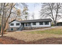 Charming home featuring stone accents, a welcoming front porch, and newly built stairs, surrounded by mature trees at 2923 Glenhaven Sw Ct, Conyers, GA 30094