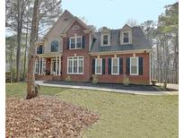 Charming two-story brick home with a manicured lawn and classic architectural details at 155 Woodcreek Ln, Fayetteville, GA 30215