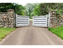 A stone and wood entrance gate leads to a private estate drive surrounded by mature trees at 2100 West Wesley Rd, Atlanta, GA 30327