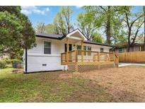 Charming white home with a welcoming wooden front porch and freshly painted white brick foundation at 2297 Sheryl Dr, Decatur, GA 30032