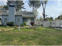 Charming home featuring a well-manicured front lawn and landscaping, a classic design, and a white picket fence at 2220 Wellington Cir, Lithonia, GA 30058