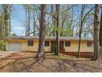 Charming single-story home with a light yellow facade and mature trees surrounding the property at 1360 Cypress Ridge Cir, Stone Mountain, GA 30083