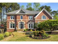Elegant two-story brick home with a well-manicured lawn, mature trees, and a welcoming front entrance at 3060 Birchton St, Johns Creek, GA 30022
