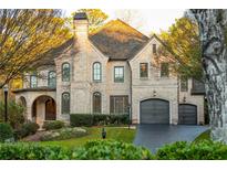 Charming two-story brick home with a manicured lawn, arched entryway, and attached two-car garage at 425 Prestwick Ct, Alpharetta, GA 30005