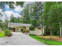 Charming single-story home with a light-colored brick exterior and a long driveway leading to a covered carport at 679 Forest Ridge Se Dr, Marietta, GA 30067