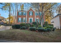 Charming brick home featuring a well-manicured lawn, green shutters, and a welcoming front entrance at 6640 Maid Marion Close, Alpharetta, GA 30005