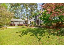 Charming home with a well-manicured lawn, stone chimney, and beautiful landscaping at 4183 Oak Crest Dr, Tucker, GA 30084