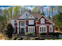 Stately brick home with manicured landscaping, large windows, and an elegant entrance framed by white pillars at 4777 Ardmore Ln, Hoschton, GA 30548