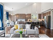 Open-concept living room flowing into kitchen, featuring modern furniture, hardwood floors, and large windows at 139 Stargaze Rdg, Canton, GA 30114