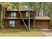 Charming brown two-story home featuring an attached garage and a welcoming front porch at 1129 Forest East Dr, Stone Mountain, GA 30088