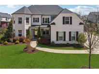 Beautiful two-story white brick home with black shutters and a well-manicured lawn at 214 Leland Way, Woodstock, GA 30188