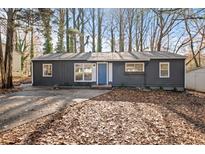 Charming exterior featuring a grey painted home, a blue door, and a leaf-covered front yard and drive at 799 Kennesaw Dr, Forest Park, GA 30297