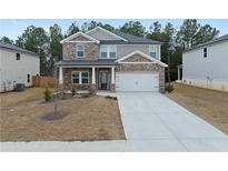 Charming two-story home with stone accents, an attached garage, and a long driveway with neat landscaping at 4171 Dean Grove Way, Loganville, GA 30052