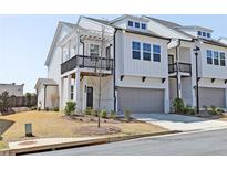 Charming two-story townhome with a gray garage door, balcony, and manicured lawn at 1433 Halpern Ln, Kennesaw, GA 30144