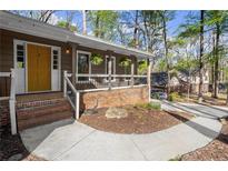 Inviting home entrance featuring a brick-accented porch with a bright yellow door and manicured landscaping at 250 Martin Ridge Ct, Roswell, GA 30076