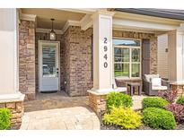 Inviting covered front porch with brick accents, stylish seating, and well-manicured landscaping at 2940 W Village Dr # 60, Suwanee, GA 30024