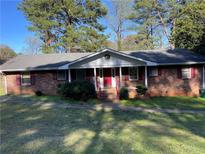 Charming brick home with a welcoming front porch and red door surrounded by lush greenery and a well-maintained lawn at 1511 Stonewood Dr, Norcross, GA 30093