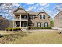 Charming two-story brick home featuring a welcoming front porch, manicured landscaping, and a well-maintained lawn at 2875 Waterstone Dr, Cumming, GA 30041