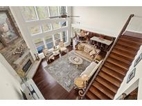 Open-concept living room with a stone fireplace, floor-to-ceiling windows, and hardwood floors offers a cozy and bright space at 2875 Waterstone Dr, Cumming, GA 30041