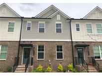 Charming townhome exterior with brick facade, gray siding, and inviting entryway at 1282 Ainsworth Aly, Sugar Hill, GA 30518