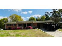 Charming single-story brick home with flowering bushes, a well-manicured lawn, and a bright blue sky at 4172 N Martin Way, Lithia Springs, GA 30122