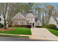 Beautiful brick home with a well-manicured lawn and a spacious driveway at 4847 Sara Creek Way, Sugar Hill, GA 30518