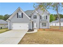 Charming two-story home with gray siding, attached garage, and well-manicured front yard at 2061 Emerald Dr, Loganville, GA 30052
