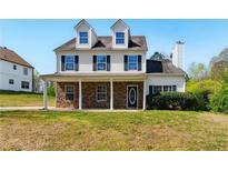 Charming two-story home featuring a stone facade, covered porch, and well-manicured lawn at 3267 Forrest Bluff Way, Lithonia, GA 30038
