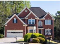 Traditional brick home featuring manicured lawn, two-car garage and classic architectural details at 2875 Factor Walk Blvd, Suwanee, GA 30024