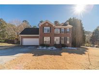 Charming two-story brick home with attached two-car garage, green lawn, and bright blue sky at 241 Rockingham Dr, Loganville, GA 30052