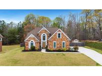 Charming brick home featuring a well-manicured lawn and a long concrete driveway at 226 Double Gate Ct, Sugar Hill, GA 30518