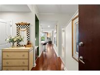 Bright condo hallway with hardwood floors leading to the open kitchen area and featuring a decorative mirror and chest at 3300 Windy Ridge Se Pkwy # 612, Atlanta, GA 30339