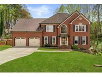 Charming brick two-story home with a well-manicured lawn, three car garage and lush landscaping at 4532 Hosta Nw Ct, Acworth, GA 30102
