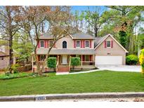 Charming two-story home featuring a well-manicured lawn, red shutters, and a two-car garage at 2611 Rock Point Ln, Snellville, GA 30039