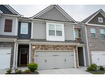Charming townhome featuring stone accents and a two-car garage for convenience and curb appeal at 5317 Radford Loop, Fairburn, GA 30213