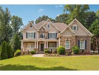 Stunning two-story home featuring a stone and brick facade with a welcoming front porch and beautifully landscaped yard at 3275 Aldrich Dr, Cumming, GA 30040