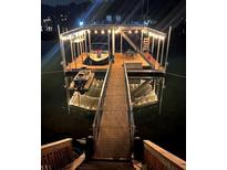 Illuminated boat dock featuring a covered boat slip, a jet ski lift, and a staircase leading to an upper deck at 6160 Lake Lanier Heights Rd, Buford, GA 30518