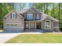 Charming two-story home with a stone and gray facade, complemented by a well-manicured lawn and an attached two-car garage at 2050 Heritage Green Dr, Marietta, GA 30064