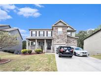 Charming two-story home features a stone facade, covered porch, manicured lawn, and a two-car garage at 6540 Muirfield Pt, Fairburn, GA 30213