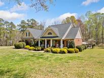Charming brick home featuring a well-manicured lawn, lush landscaping, and inviting front porch with rocking chairs at 5660 Trout Creek Dr, Douglasville, GA 30135