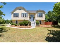 Charming yellow two-story home featuring a well-maintained front yard with mature landscaping at 3540 Owl Brow Ct, Cumming, GA 30028