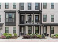 Charming townhome with a balcony, white brick, black trim, and well manicured landscaping at 4651 Eddibunn Se Dr, Smyrna, GA 30080