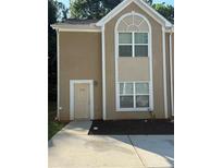 Inviting townhome featuring a neutral stucco facade, complemented by crisp white trim and a well-manicured landscape at 2960 Fields Dr, Lithonia, GA 30038