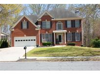 Charming two-story red brick home with well-maintained lawn and two-car garage at 3220 Warren Creek Dr, Powder Springs, GA 30127