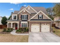 Beautiful home featuring stone and siding, a red front door, manicured landscaping, and a two car garage at 552 Lawton Bridge Sw Rd, Smyrna, GA 30082