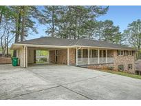 Inviting brick ranch-style home showcasing a covered carport and charming front porch at 4089 Menlo Dr, Tucker, GA 30084