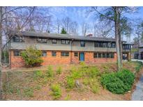 Charming two-story home with a brick facade and a lush, natural landscape around the property at 120 Maryeanna Ne Dr, Atlanta, GA 30342