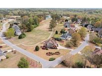Beautiful aerial view of a red brick home with manicured lawn in a lovely neighborhood with a pond in the distance at 179 Country Club Dr, Hiram, GA 30141