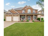 Charming brick home with a welcoming front porch, manicured lawn, and attached two-car garage at 5085 Mundy Dr, Cumming, GA 30028